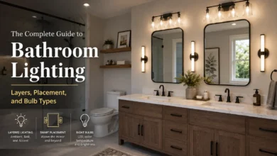 Modern bathroom featuring layered lighting with a halo-lit round mirror, wall sconces, recessed ceiling lights, a glass walk-in shower, freestanding bathtub, and an infographic explaining ambient, task, and accent lighting alongside a color temperature guide for bathroom lighting.
